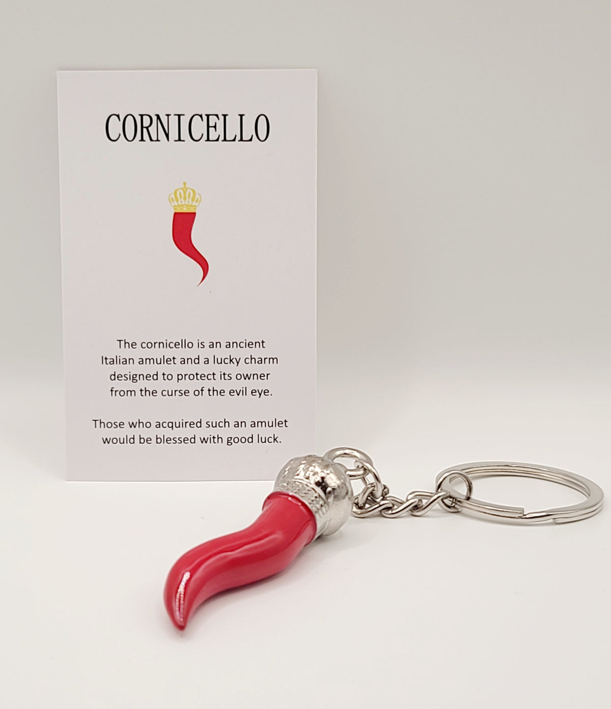 Red cornicello keychain with silver accent accompanied by a Cornicello branded card.
